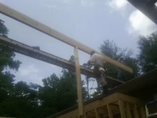 Carpenter setting a ridge beam over a new addition frame — Ice Dam Removal by Roofing Brothers in Commack