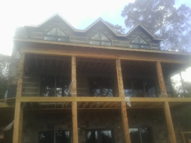 Dormers and porch framing on a large log home under construction — Roof Coating work by our crew in Commack