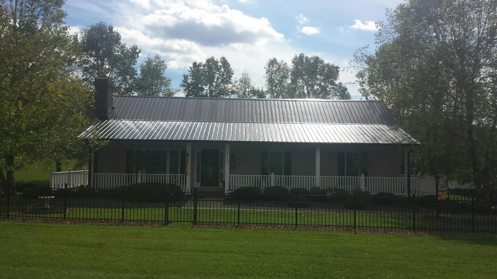 Gray metal roof on a brick ranch with a full width front porch — Gutter Guard Installation work by our crew in Commack